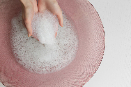 Woman washing hands in bowl isolated on whiteの写真素材