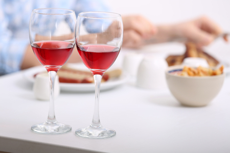 Dinner with glasses of wine on light blurred backgroundの写真素材