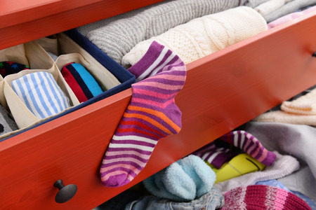 Woman's sock and pile of clothes in open drawer, close upの写真素材