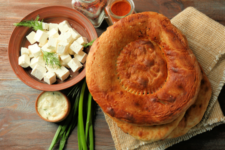 Fresh fried bread with cheese, saucer and spring onion on wooden table closeupの写真素材
