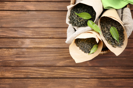 Dry tea with green leaves in cornets on wooden table backgroundの写真素材