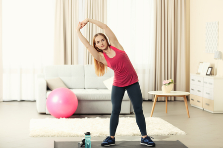 Young sportswoman doing exercises on a mat at homeの写真素材