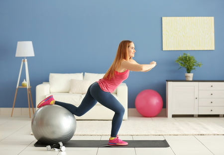 Young sportswoman doing exercises with ball on a mat at homeの写真素材