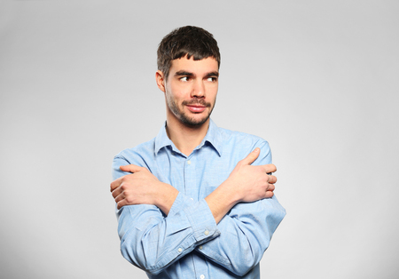 Young man standing in blue shirt on grey backgroundの写真素材