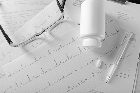 Cardiogram chart with plastic bottle of pills on table, top viewの写真素材