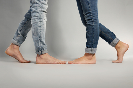 Young couple in blue jeans standing on grey backgroundの写真素材