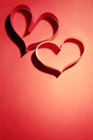 Valentine's Day heart made of ribbon on red backgroundの写真素材