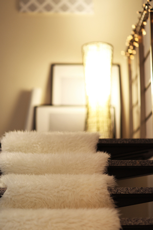 Modern stairs with electric garland, white furry bedspread and lampの写真素材