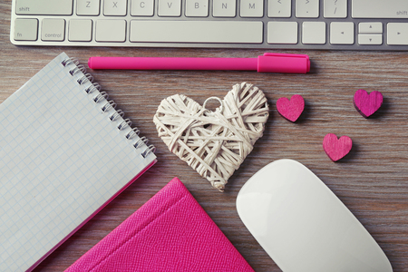 Computer peripherals with hearts, pen and notebooks on wooden tableの写真素材