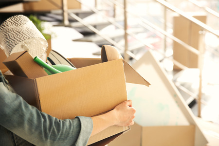 Young woman holding open cardboard box with things for moving into new houseの写真素材