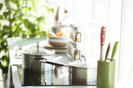 Modern electric stove with utensils in the kitchen beside window, close upの写真素材