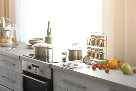 Modern kitchen interior with white furniture and electric stove beside the windowの写真素材