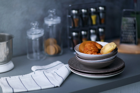 Utensils, towel and croissants on modern kitchen table, close up