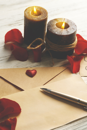 Gift card for Valentine's Day with pen and candles on white wooden backgroundの写真素材