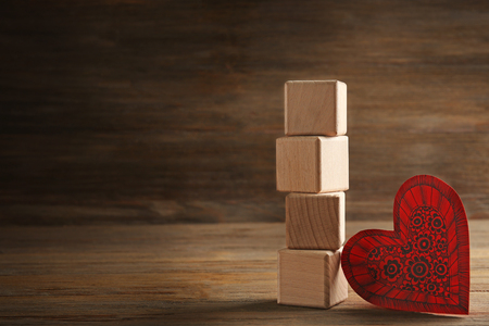 Four wooden cubes with red paper heart on wooden background. I love you inscriptionの写真素材