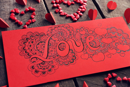 Red gift card with love doodle drawing on wooden backgroundの写真素材