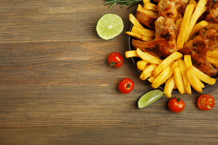 Baked chicken wings with French fries on wooden tableの写真素材