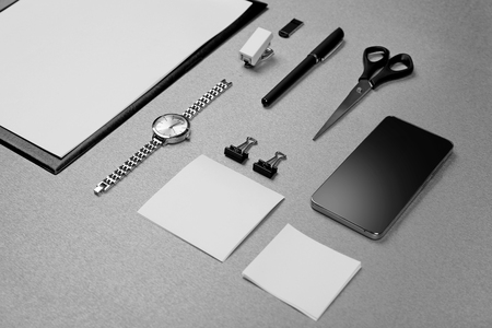 Office set with white sheets of paper, mobile phone, watch and stationery on grey backgroundの写真素材