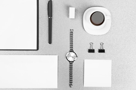 Office set with white sheets of paper, cup of coffee, watch and stationery on grey backgroundの写真素材