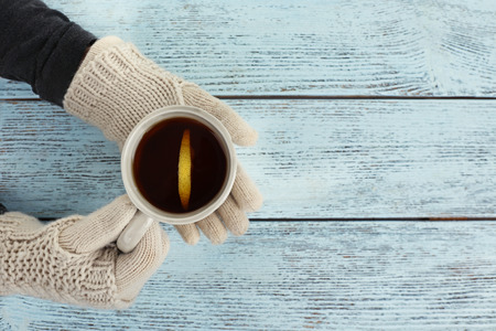 Female hands holding cup of hot drink, on wooden table backgroundの写真素材
