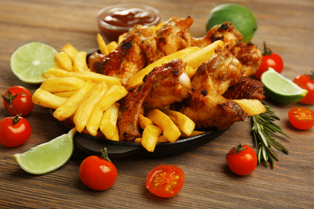 Baked chicken wings with French fries on wooden tableの写真素材