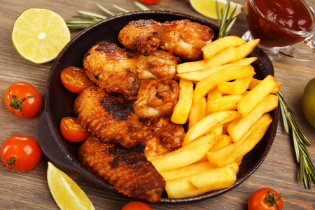Baked chicken wings with French fries on wooden tableの写真素材