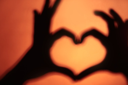 Hand shaped heart on orange background