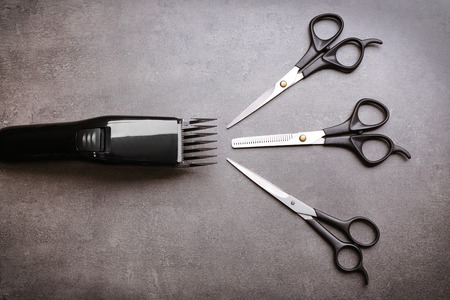 Barber set with hair trimmer and scissors on grey background
