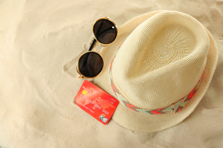 Bank card with male hat and sunglasses on sand backgroundの写真素材