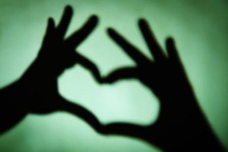 Hand shaped heart on green backgroundの写真素材
