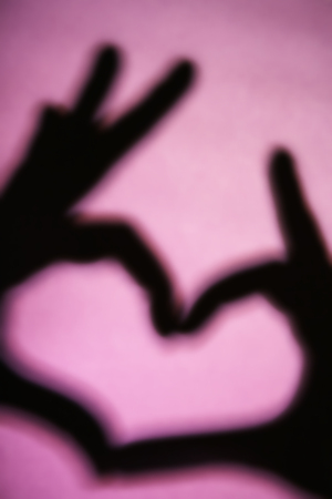 Hand shaped heart on purple background