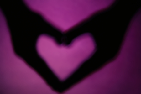 Hand shaped heart on purple backgroundの写真素材