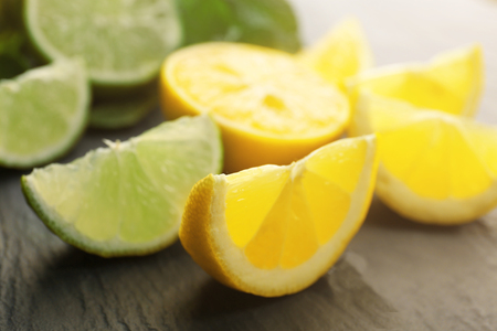 Slices of fresh lemon and lime with green leaves on table closeupの写真素材