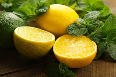 Sliced fresh lemons and lime with green leaves on wooden table closeupの写真素材