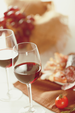 Glasses of red wine with food on table closeupの写真素材