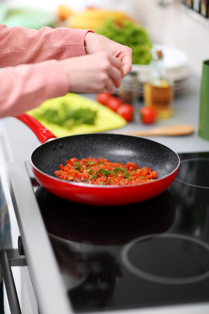 Female hands cooking on kitchen with frying pan, closeupの写真素材