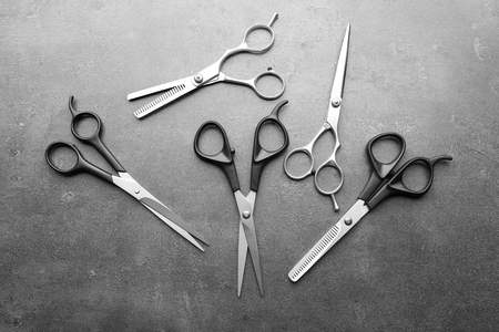 Professional metal scissors laying chaotically on a dark grey surface, close upの写真素材