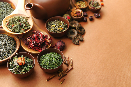 Variety of dry tea in bowls with teapot on light brown background, closeupの写真素材
