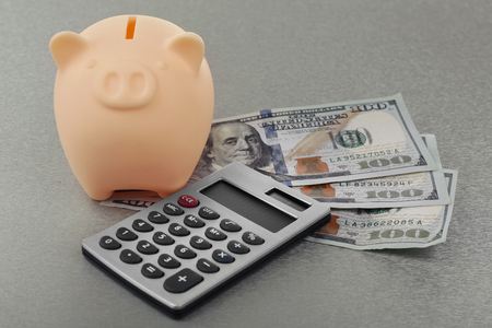 Beige piggy bank with dollar banknotes, calculator on grey backgroundの写真素材