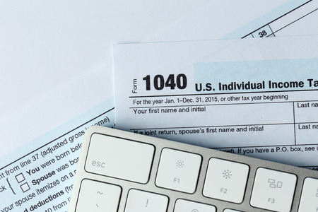 1040 Individual Income Tax Return Form for 2015 year with a computer keyboard on the white desk, close upの写真素材