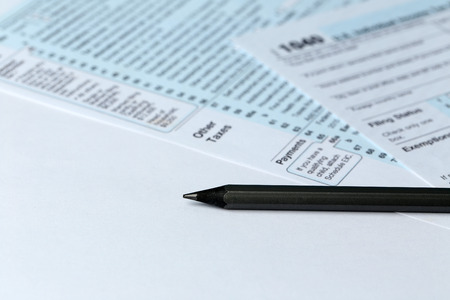 1040 Individual Income Tax Return Form for 2015 year with a pencil to fill on the white desk, close upの写真素材