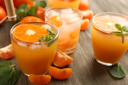 Tangerine cocktails with sliced mandarins, ice, mint on a wooden table, close upの写真素材