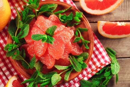 Juicy grapefruit pieces with fresh mint on a plate, close upの写真素材