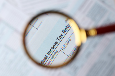 1040 Individual Income Tax Return Form  under magnifying glass, top viewの写真素材