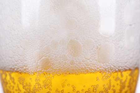 Glass of light beer with froth and bubbles, close upの写真素材