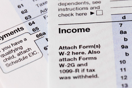 Part of the 1040 Individual Income Tax Return Form for 2015 year on the white wooden desk, close up