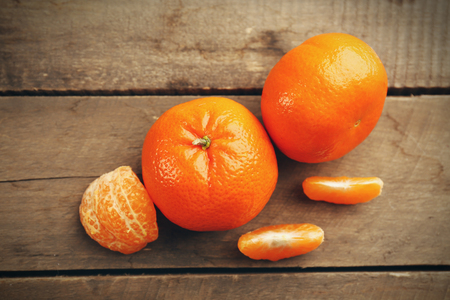 Unpeeled tangerines  with slices on the wooden table, top viewの写真素材