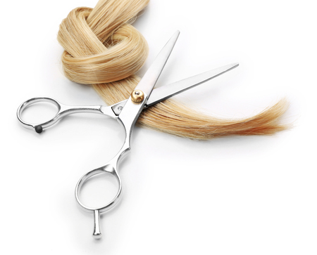 Hairdresser's scissors with strand of blonde hair, isolated on whiteの写真素材