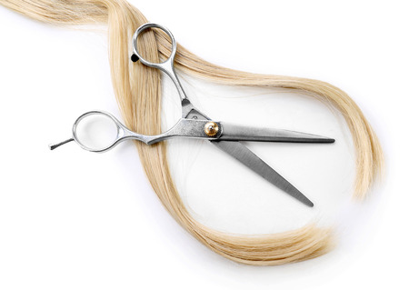 Hairdresser's scissors with strand of blonde hair, isolated on whiteの写真素材