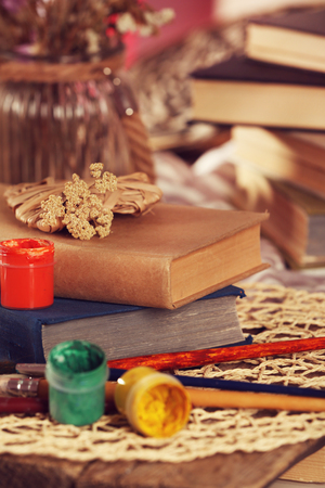 Stack of old books with paints and brushes on a table, close upの写真素材